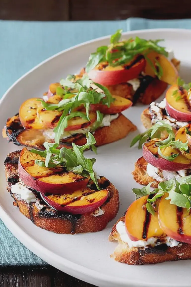 Grilled nectarine and cheese crostini garnished with fresh basil on a rustic wooden table.