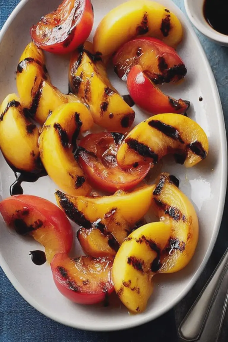 Close-up of grilled stone fruits with balsamic syrup on a rustic wooden table.