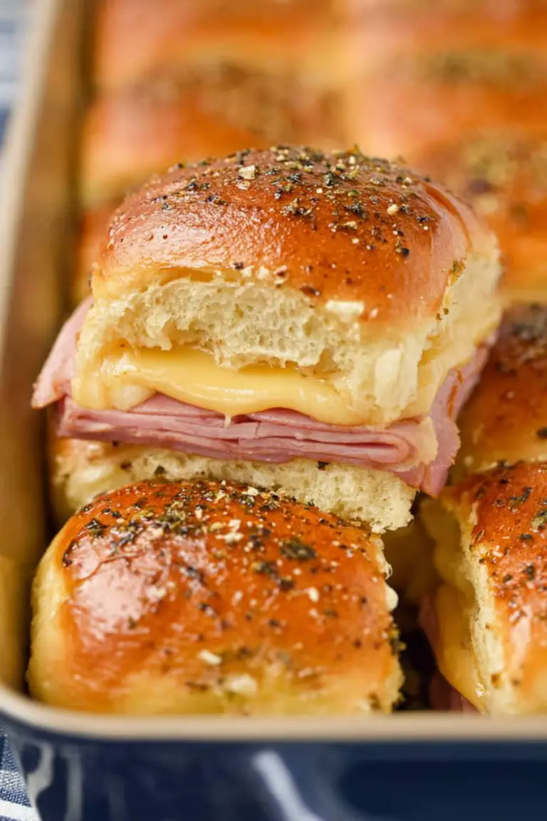 Delicious freshly baked ham and cheese sliders on a wooden platter, topped with poppy seeds.