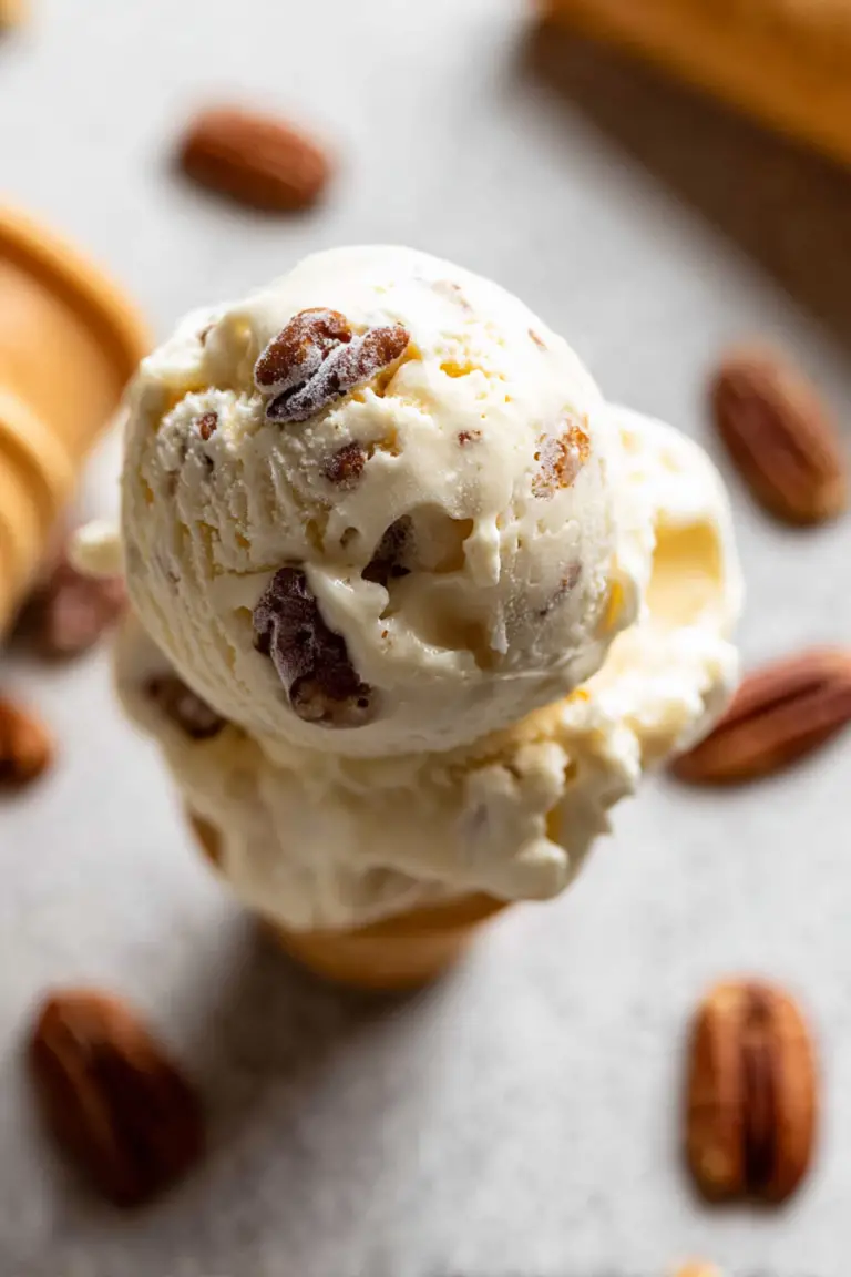 Delicious homemade butter pecan ice cream in a bowl with pecan nuts and maple syrup on top.