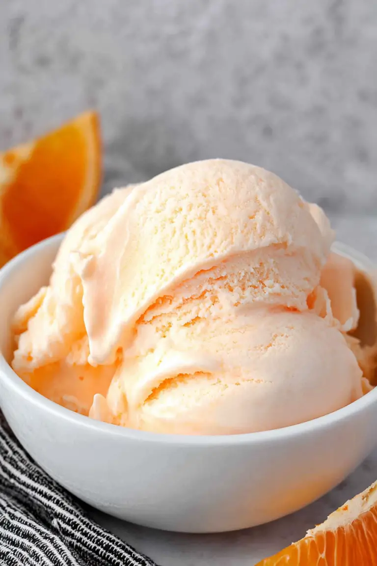 Delicious homemade orange ice cream in a bowl garnished with fresh orange slices.