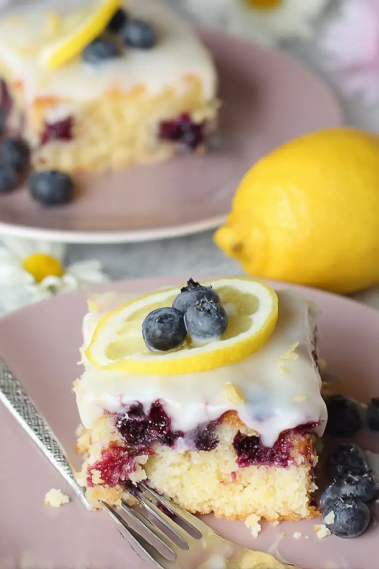 Delicious lemon blueberry sheet cake with glaze and fresh blueberries on a rustic wooden table.