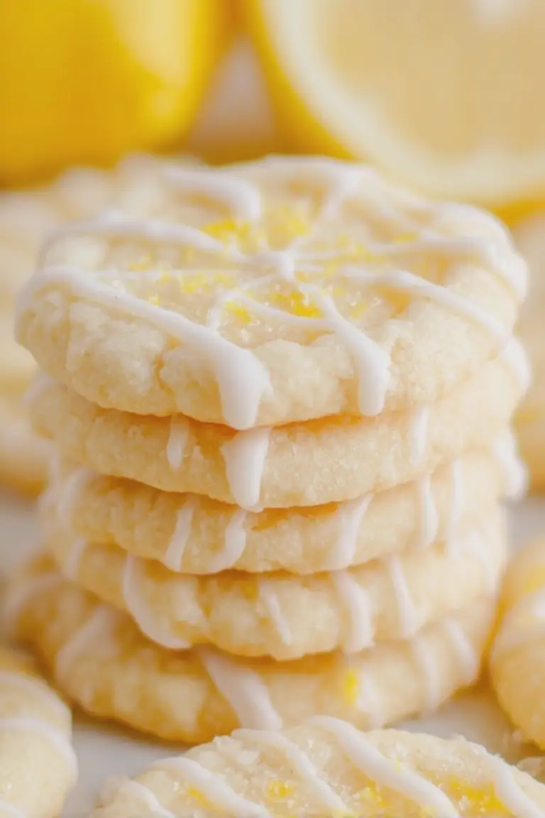 Freshly baked lemon sugar cookies with powdered sugar and lemon glaze on a wooden table.