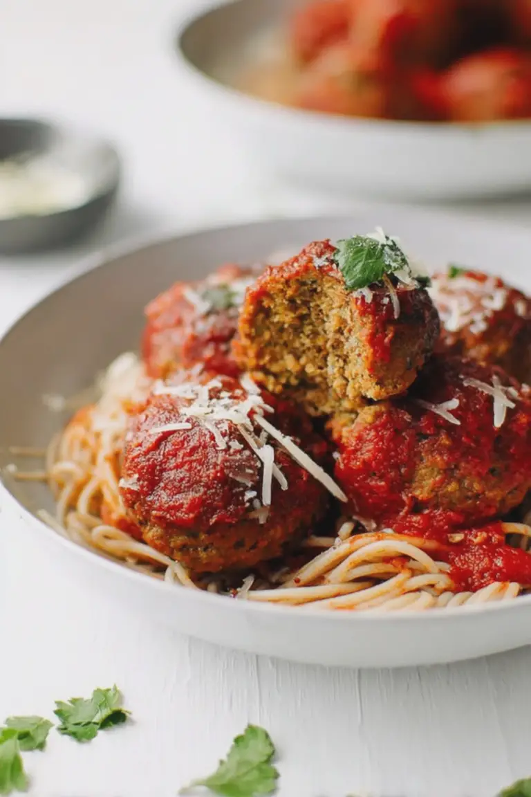 Moist baked lentil meatballs on spaghetti with marinara sauce and fresh basil, showcasing a hearty vegetarian meal.