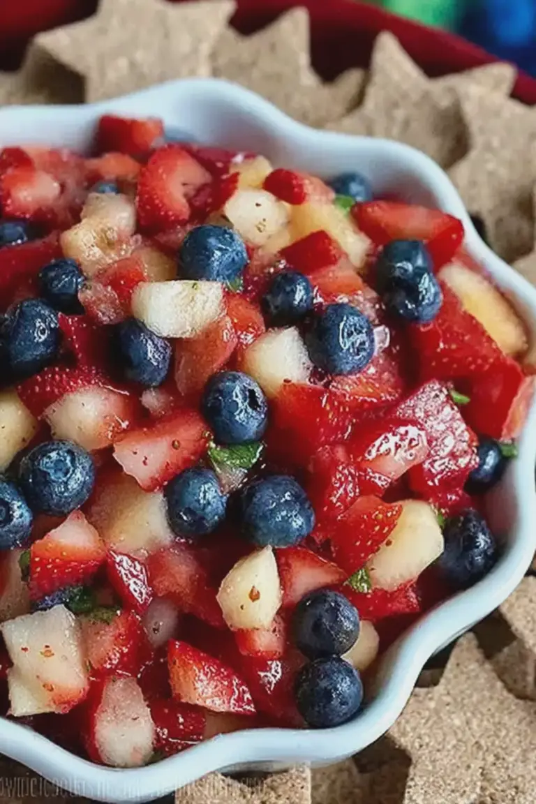 Bowl of colorful summer fruit salsa with blueberries, strawberries, apples, and tortilla chips on the side.