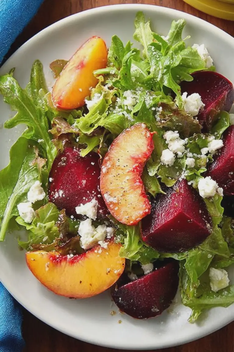 Nectarine and beet salad with mixed greens and feta cheese in a colorful bowl.