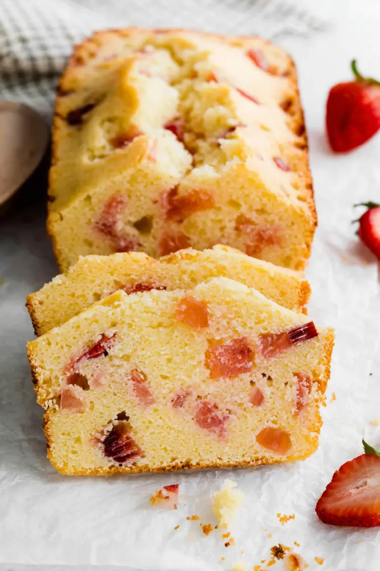 Slices of moist strawberry rhubarb pound cake garnished with fresh fruit on a rustic wooden table.